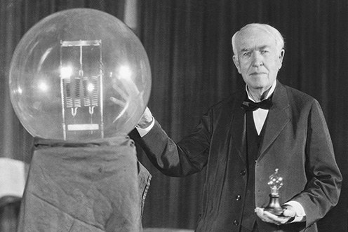 Thomas Edison holding a large early incandescent light bulb