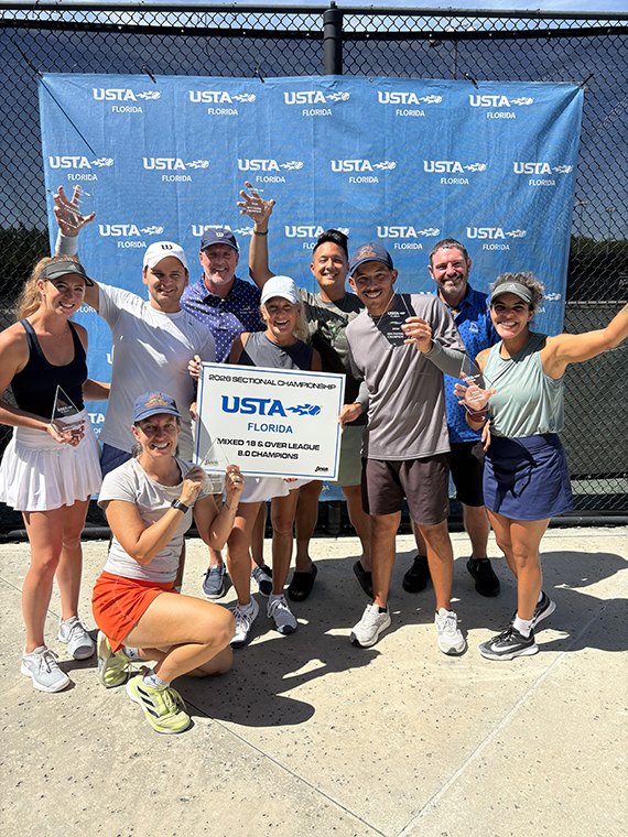 Mixed doubles team holding the USTA Florida sectional championship sign on court