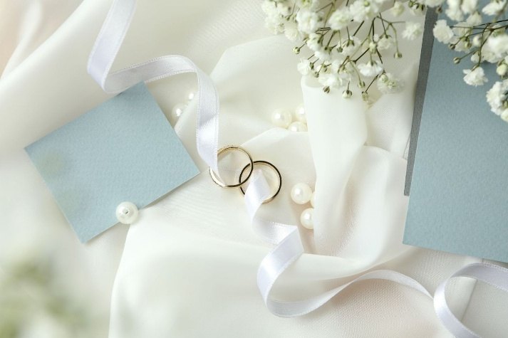 Two gold wedding rings on white satin with baby's breath